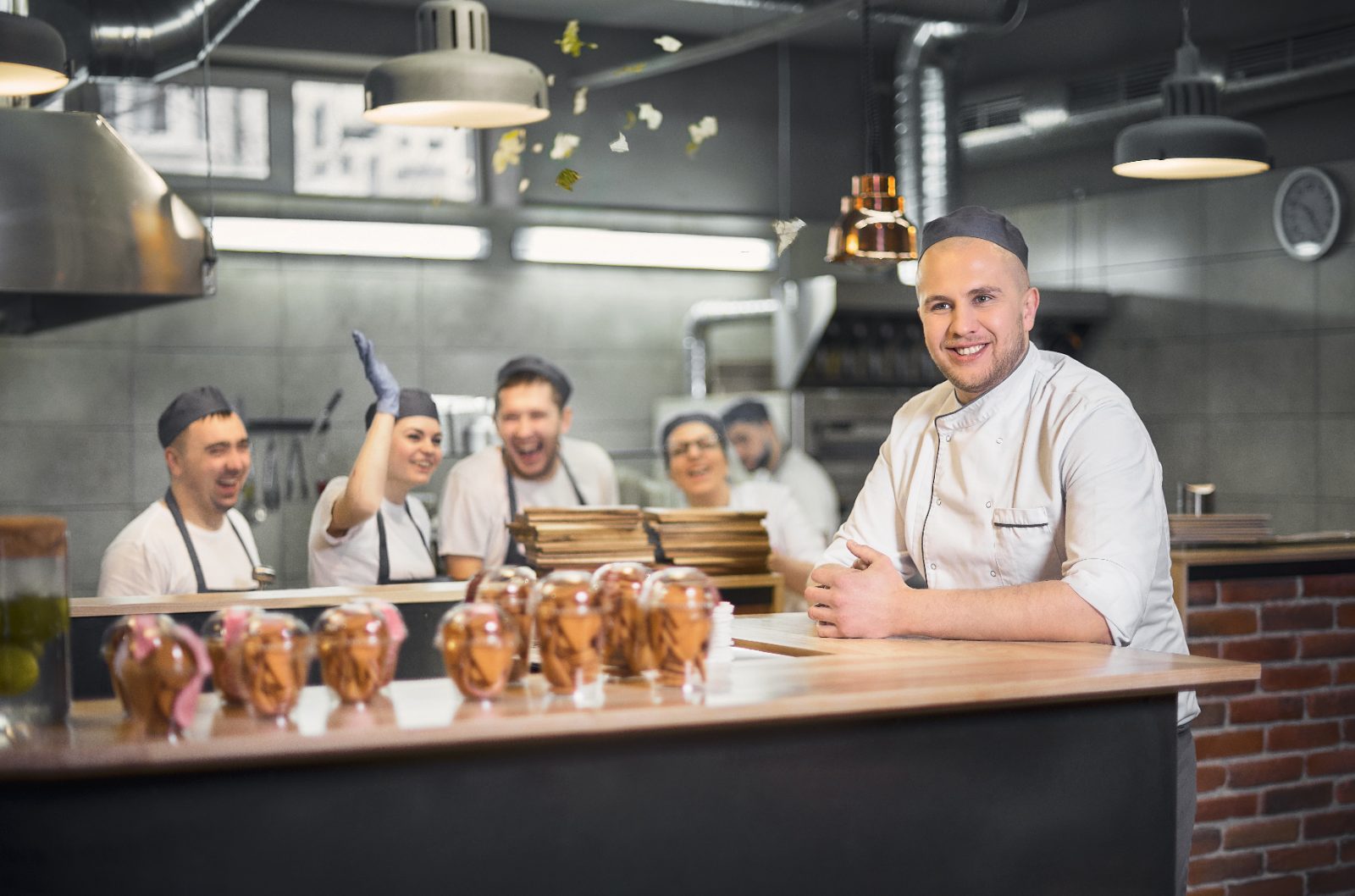 Cook smiling in a busy kitchen with his team working behind him